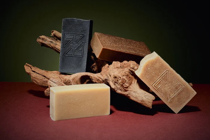 Handcrafted turmeric and camwood cold process soap bar with a rich golden-brown color, made with shea butter and olive oil, displayed on a natural-toned wooden stick.