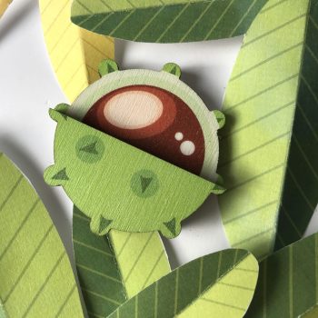 conker brooch sat in paper leaves