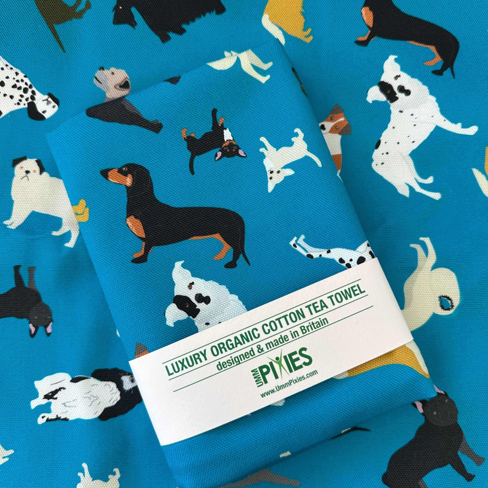 Dogs New Tricks Tea Towel shown in retail packaging on an opened example of the tea towel