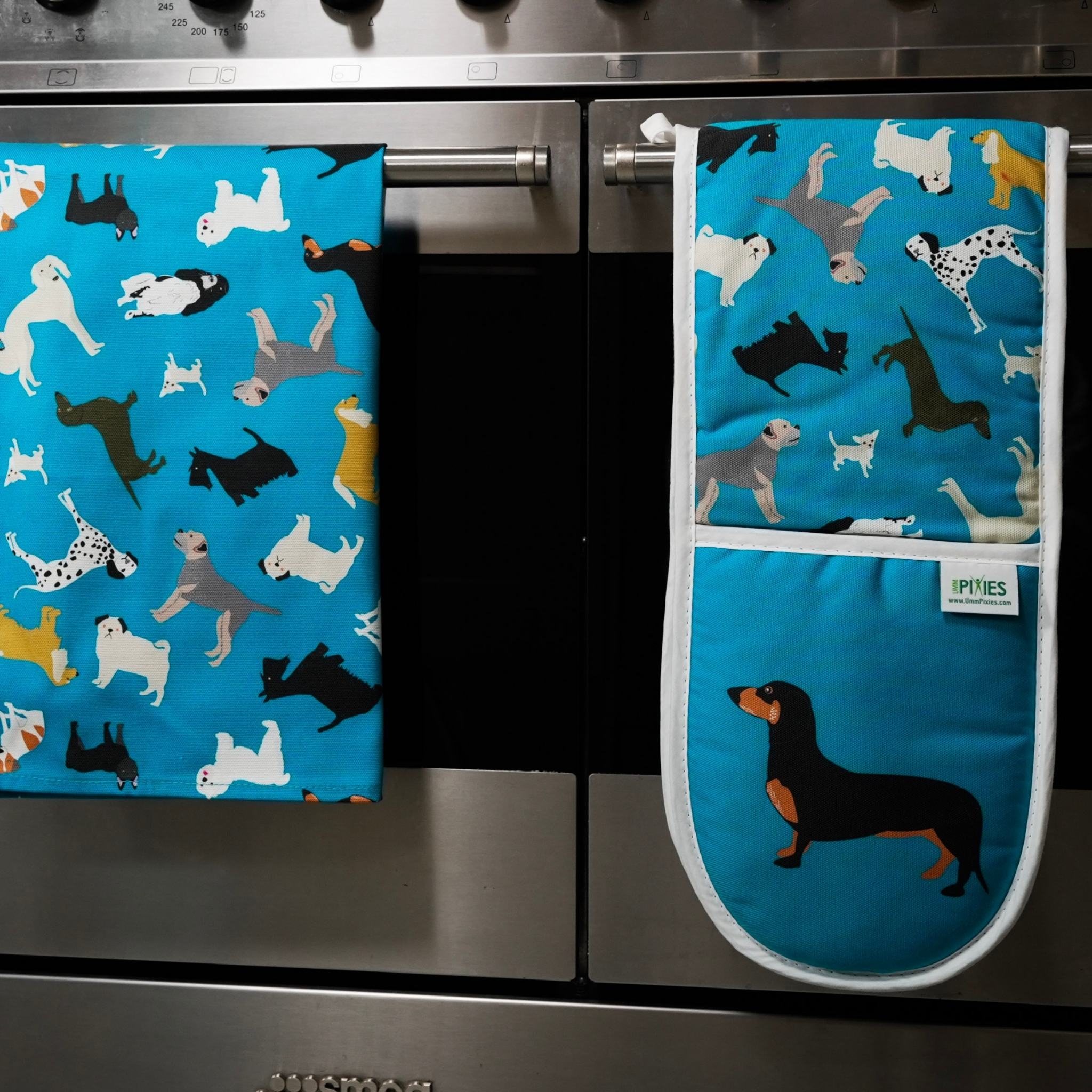 Dogs design cotton oven gloves shown on oven door with matching tea towel