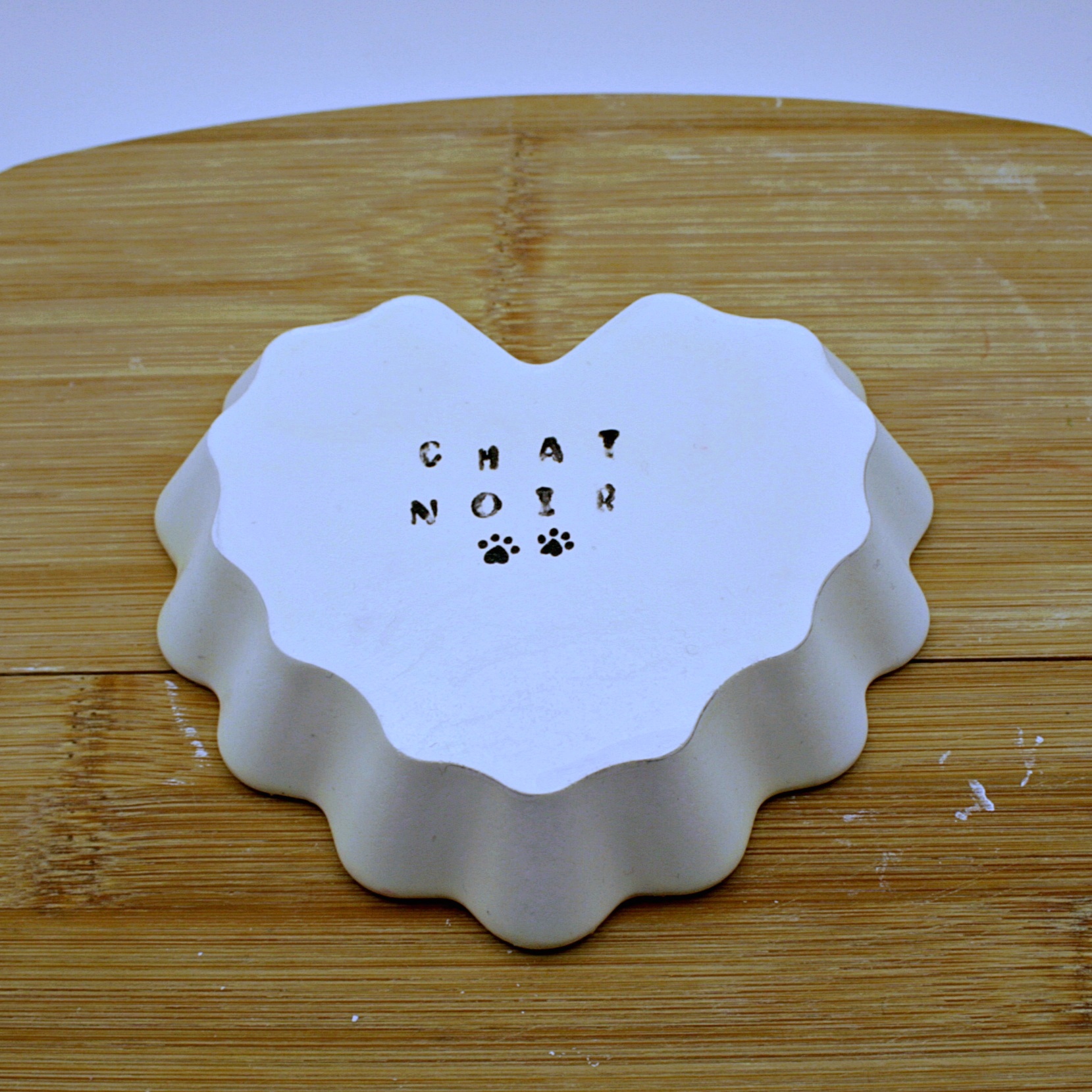 Back of Heart shaped tray white with a floral motif and a black cat